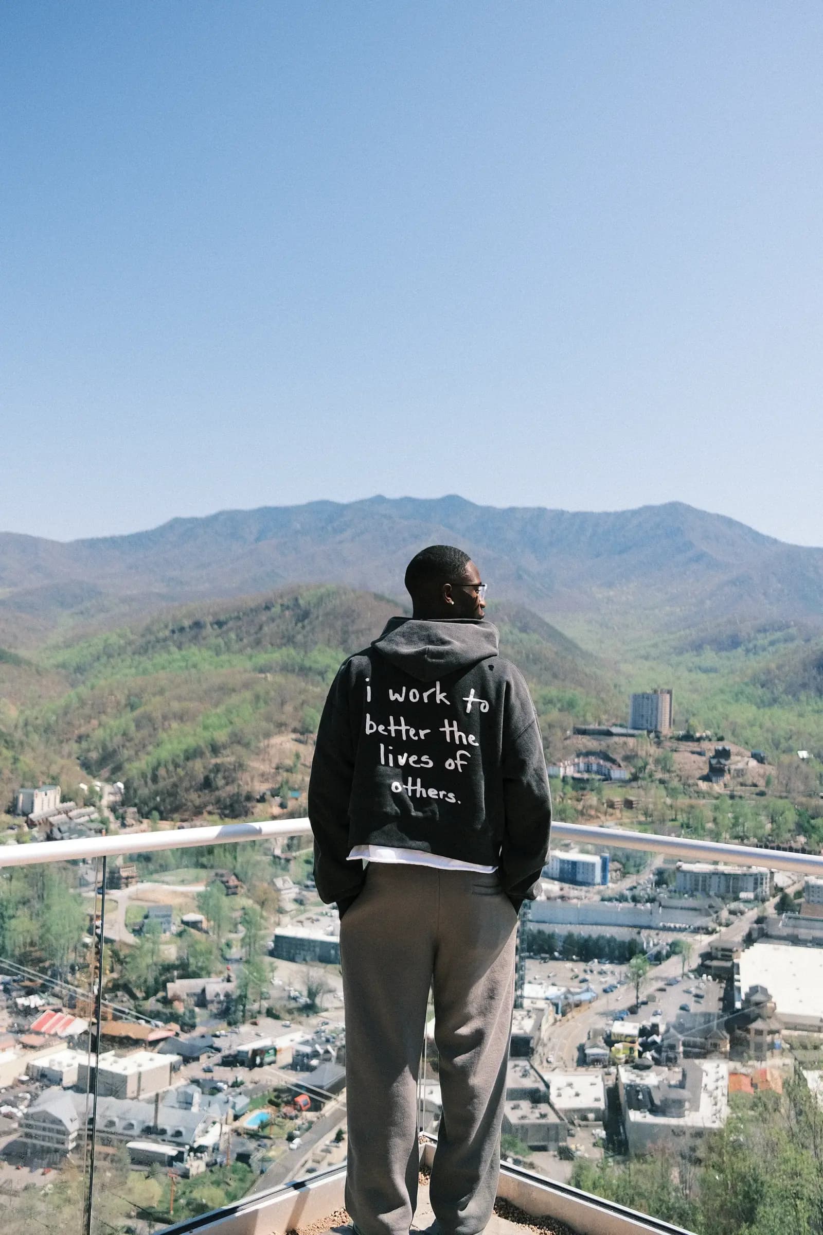 Creator on a hilltop wearing the 'I work to better the lives of others' hoodie